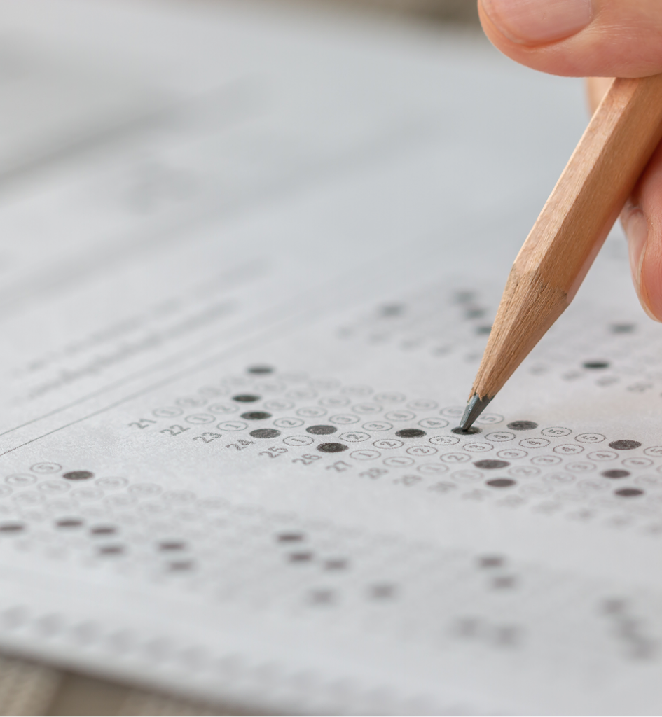 Student hand testing doing test exam with pencil drawing selected choices on answer sheet in school final exams at college or university.